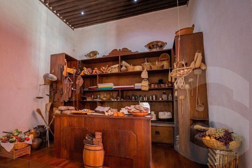 A rustic kitchen with wooden shelves, hanging utensils, and a variety of kitchenware. 5