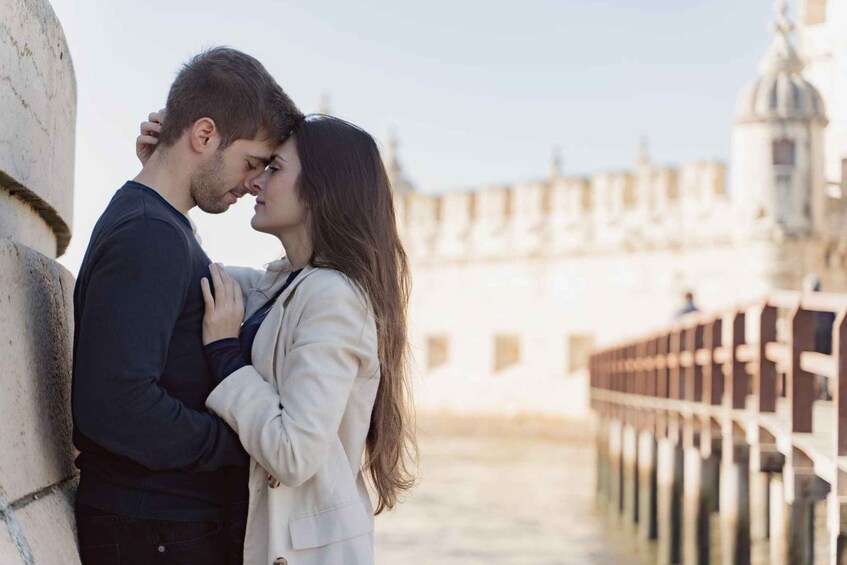 A couple embracing on a bridge with a historic building in the background. 5