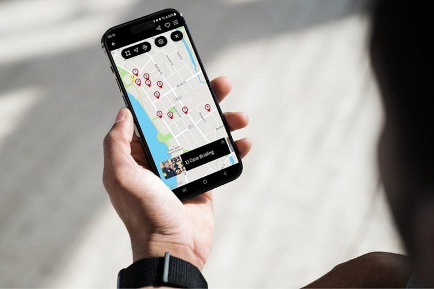 A person holding a smartphone with a map application displaying various locations marked with red pins. 4