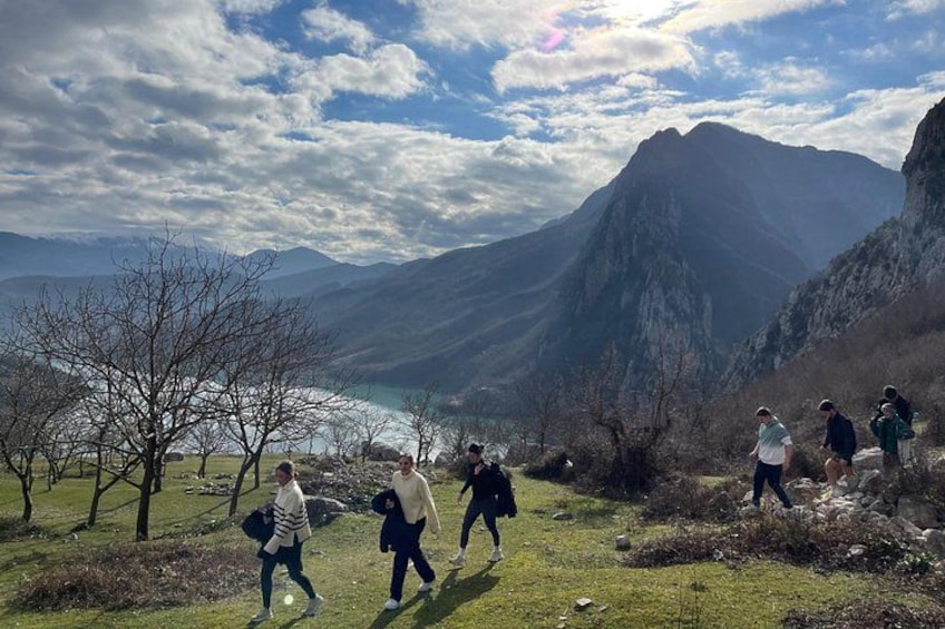 A group of hikers on a mountain trail with a lake and mountains in the background. 3