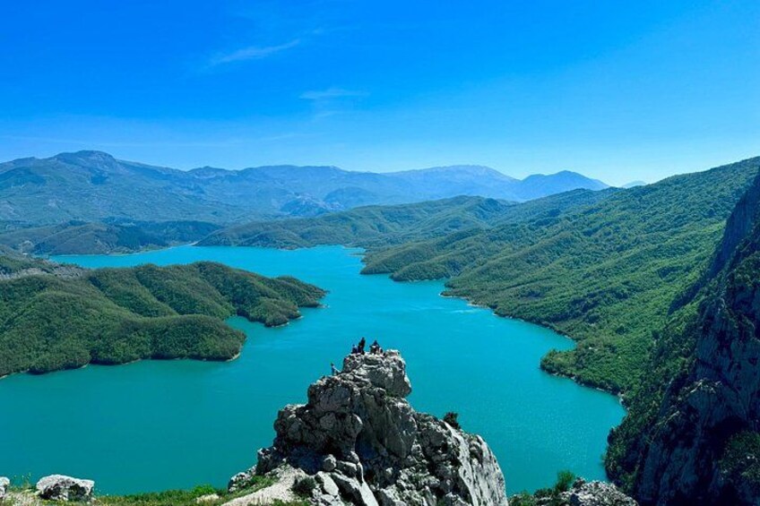 A turquoise lake surrounded by green hills and mountains. 2