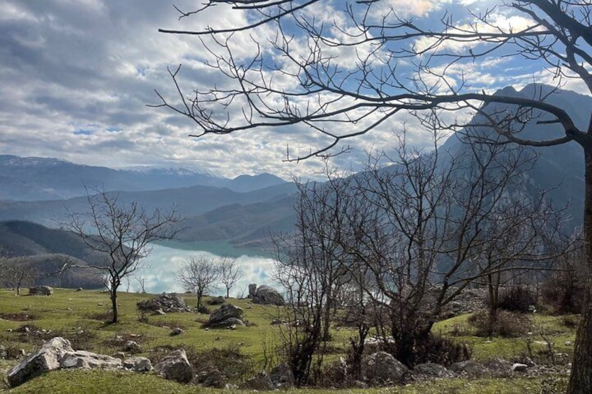 A mountainous landscape with a lake, rocky terrain, and leafless trees. 2