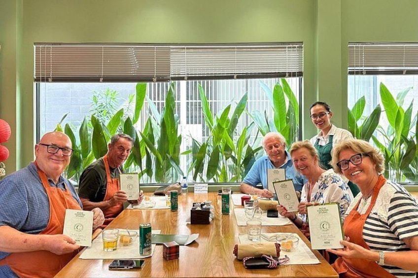 Un groupe de personnes est assis autour d’une table, des certificats sont posés devant elles, dans une pièce dotée de grandes fenêtres et agrémentée de plantes vertes. 3
