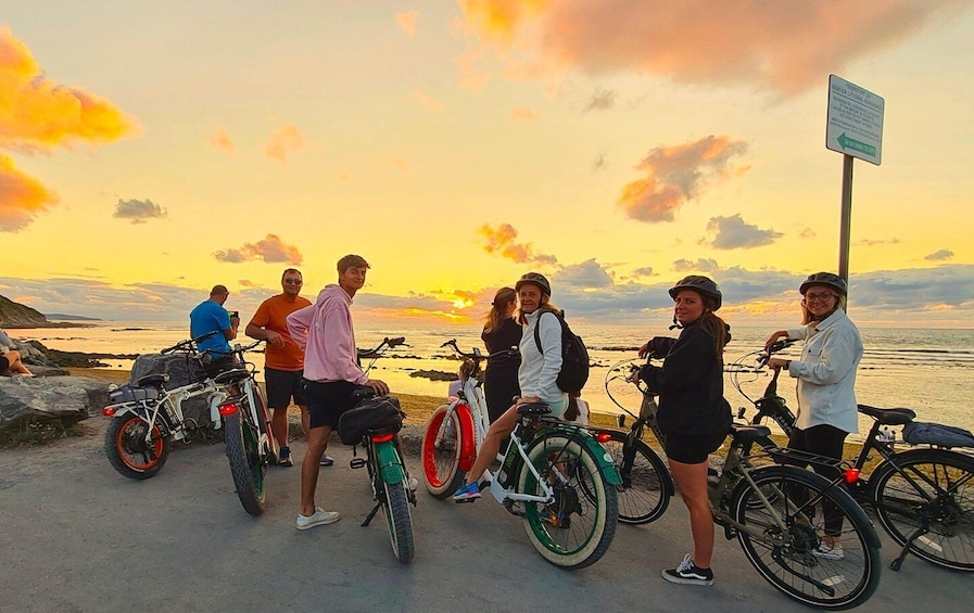 A group of people with bicycles by the seaside at sunset. 2