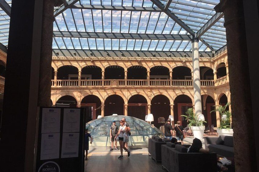 An indoor courtyard with a glass roof, columns, and seating areas. 4
