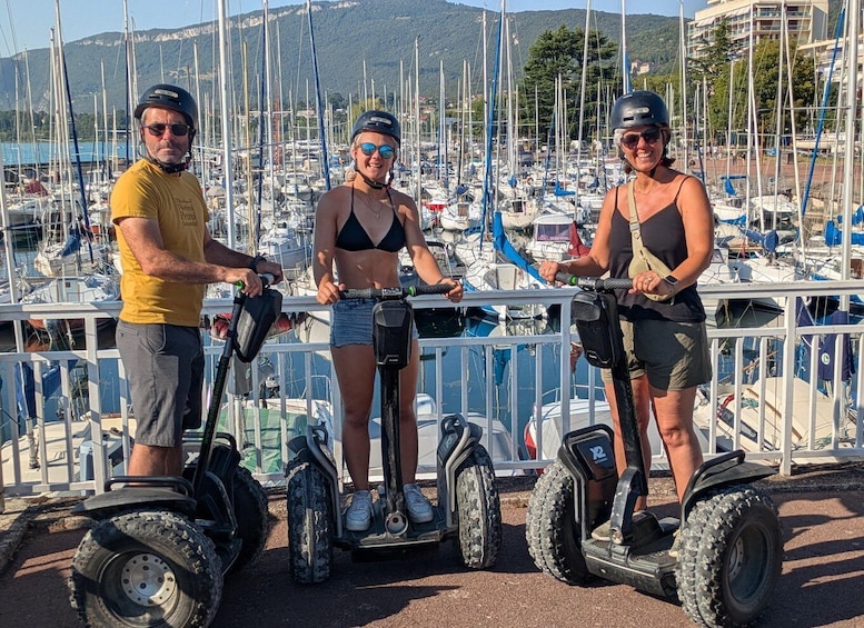 Three people on Segways at a marina with boats and hills in the background. 5