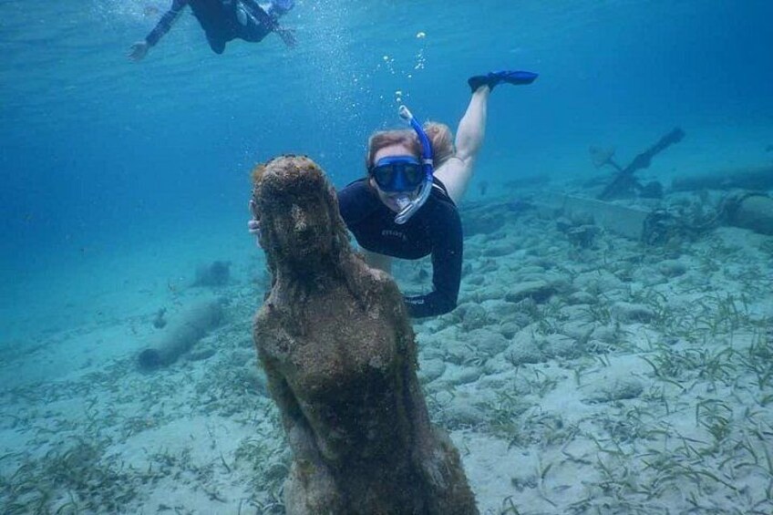 A diver underwater near a large, weathered statue. 4