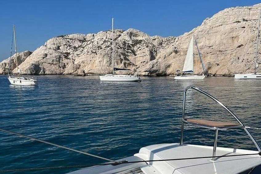 A marina with boats, rocky cliffs, and clear blue water. 3