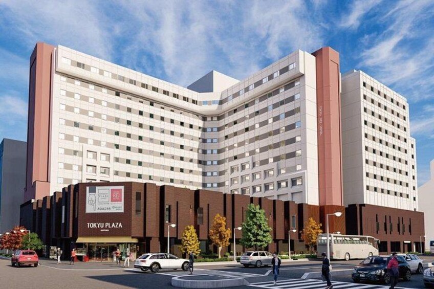 A multi-story hotel with a prominent 'TOKYU PLAZA' sign, surrounded by trees and vehicles on the street. 3