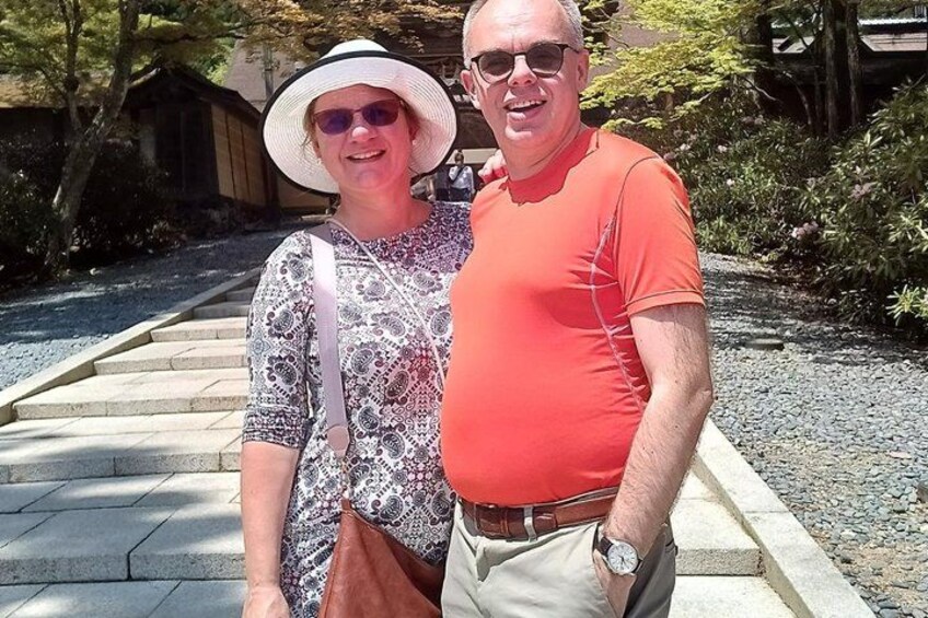 A man and woman standing on a stone pathway with greenery in the background. 4