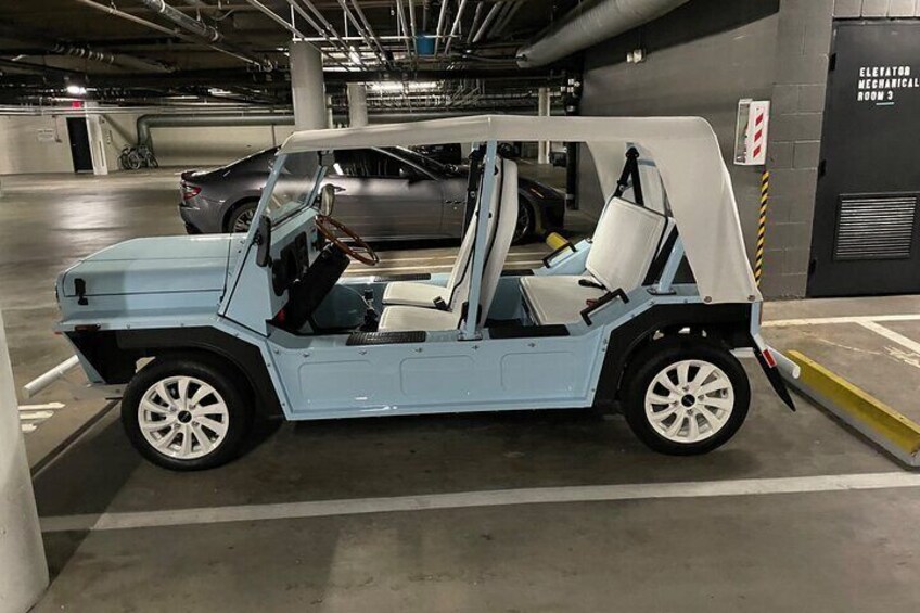 A light blue vehicle with white seats parked in a garage. 2