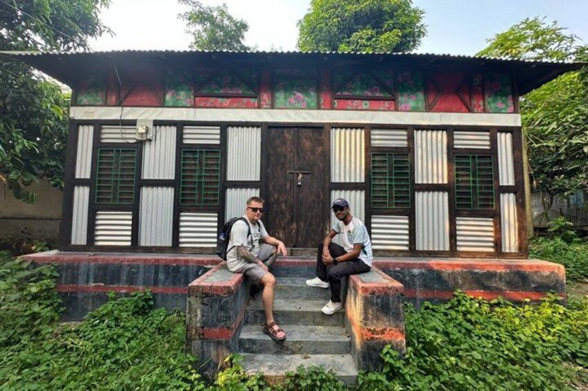 A man sitting on steps in front of a building with green shutters and a colorful facade. 2