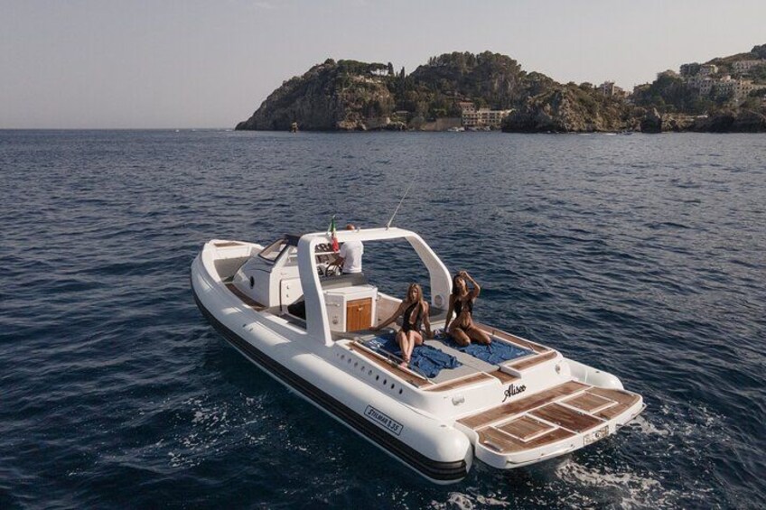 A motorboat with two people on board, sailing on a calm sea with a rocky coastline in the background. 4