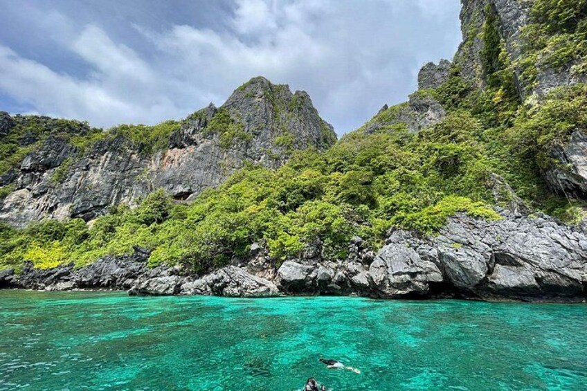 A clear turquoise sea, rocky cliffs, and lush green vegetation. 3