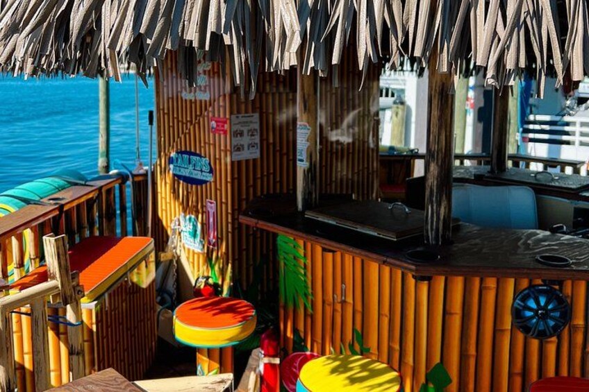 A wooden bar with a thatched roof, a sign for 'FISHING', and a view of the ocean. 3