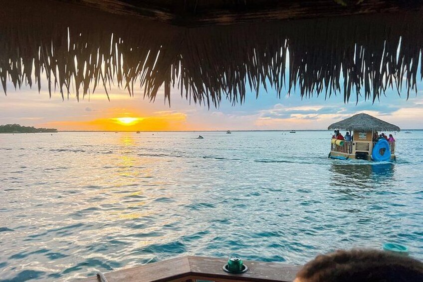 A boat with a thatched roof, a sunset, and calm sea. 5