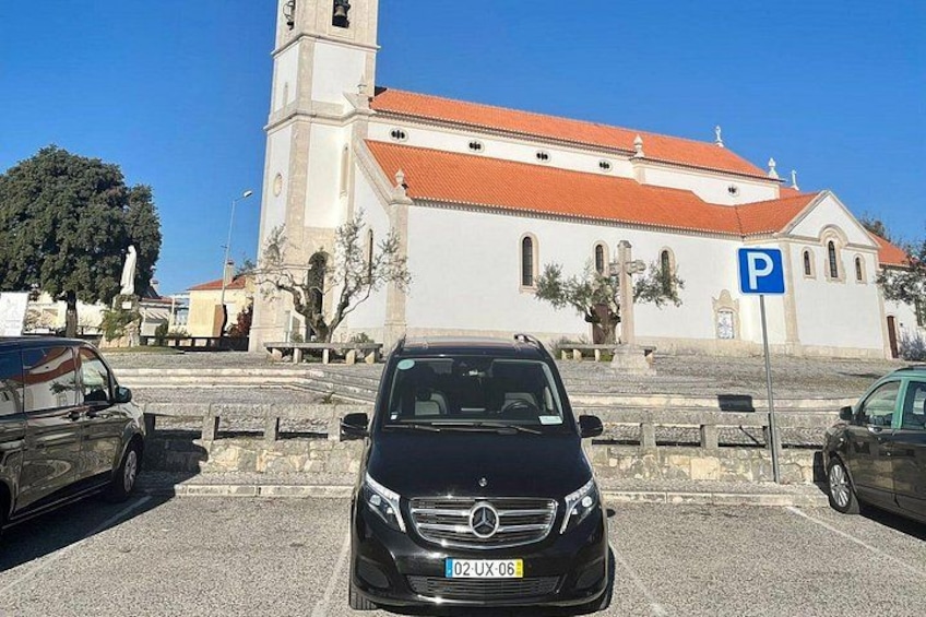 Una iglesia con un campanario, coches aparcados y un cartel de estacionamiento. 2