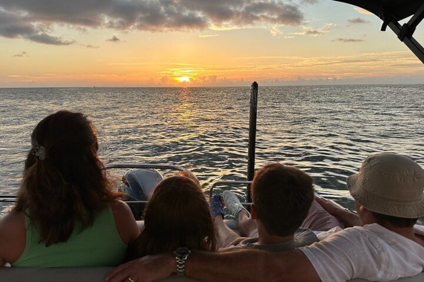 A sunset over the ocean with a boat and people on it. 1