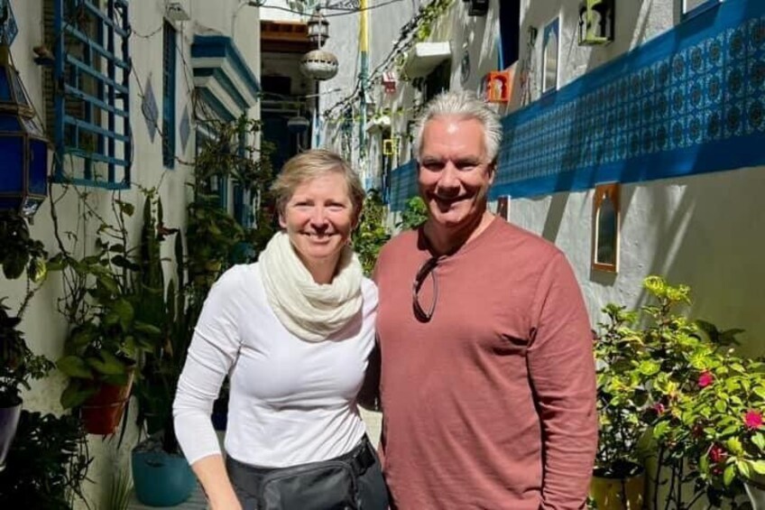 Two people standing in a narrow alley with buildings on either side. 1