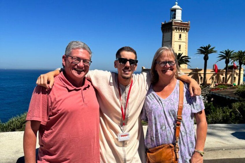 Three people standing in front of a coastal view with a lighthouse in the background. 2