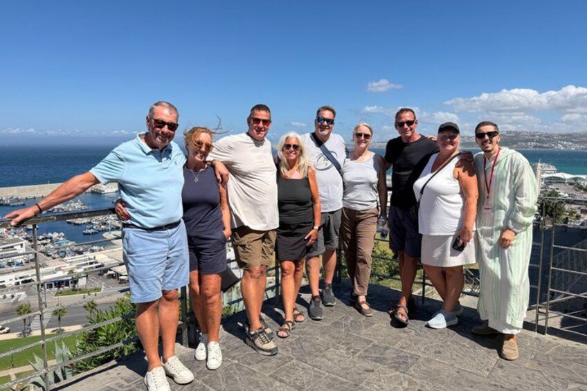 A group of people standing on a terrace with a view of the sea and boats. 4