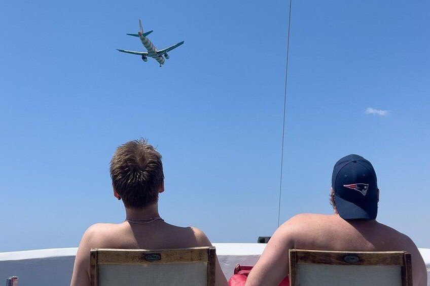 Two people on a boat watching an airplane. 5