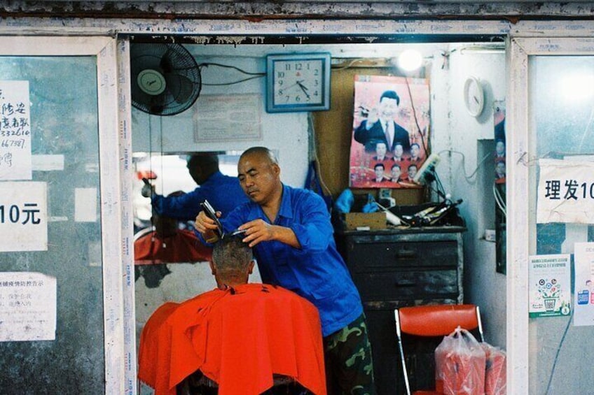 A barber cutting a man's hair in a small shop. 2