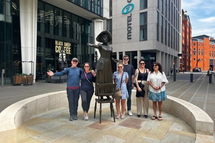 Un grupo de personas de pie frente a una escultura y un edificio con un letrero que dice 'Black Sheep Coffee'. 1