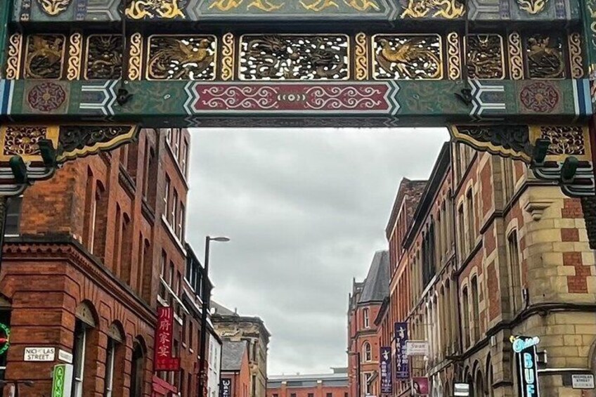 Una calle con arcos ornamentales, edificios de ladrillo y señalizaciones que incluyen 'Nicholas Street'. 5