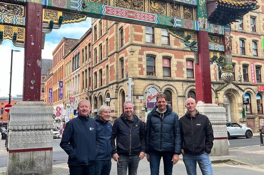 En gruppe mennesker står foran en bygning med detaljeret arkitektur og en traditionel buegang. 5