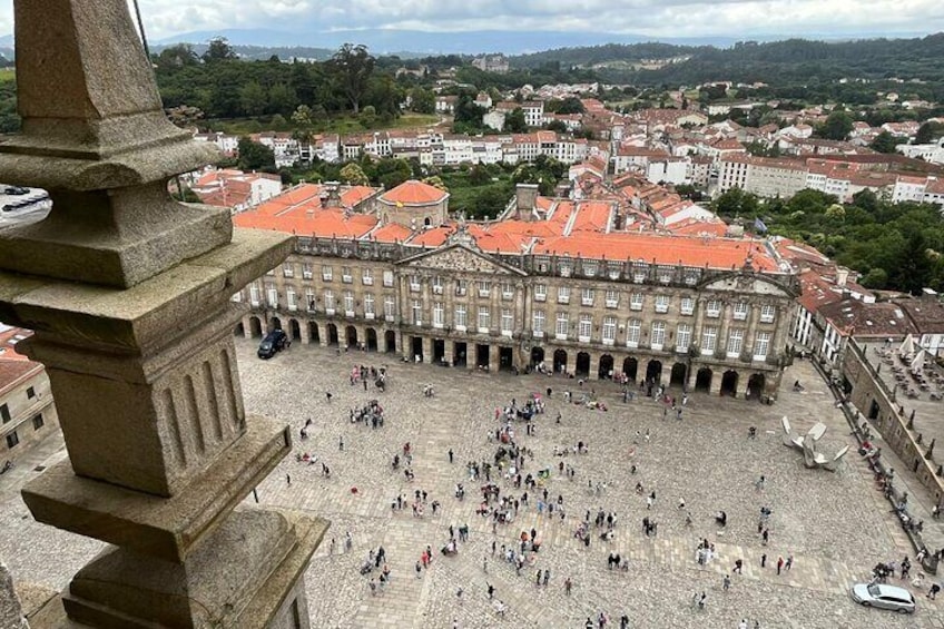 A historic square with a large building in the background, surrounded by trees and smaller buildings. 1
