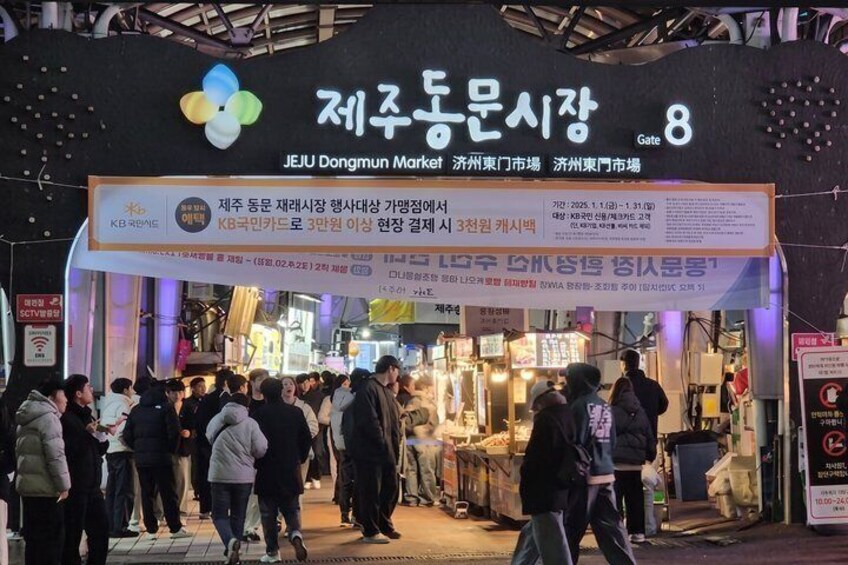 A busy market entrance with a large sign indicating Gate 8. 2