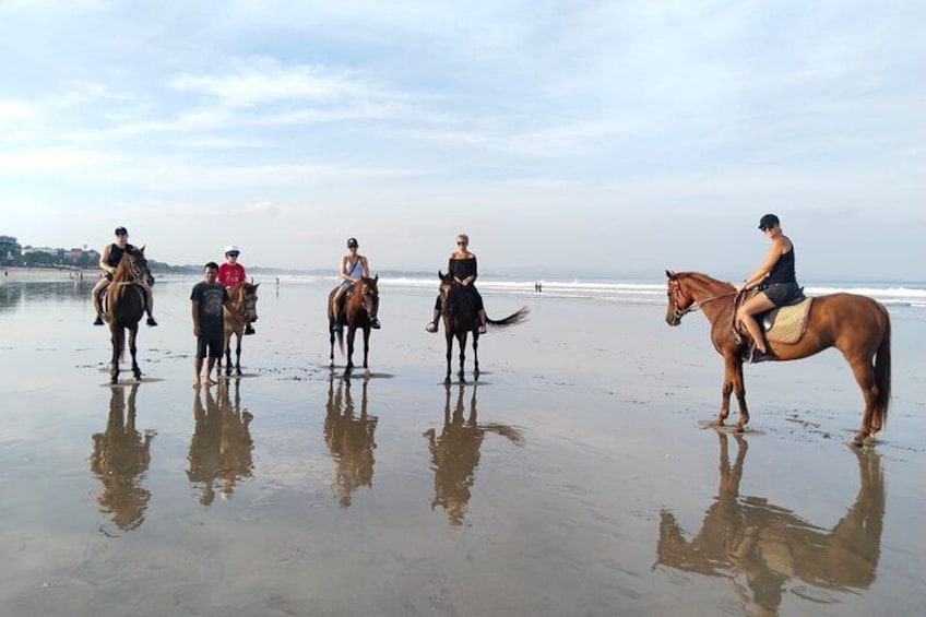 A beach with people riding horses. 3