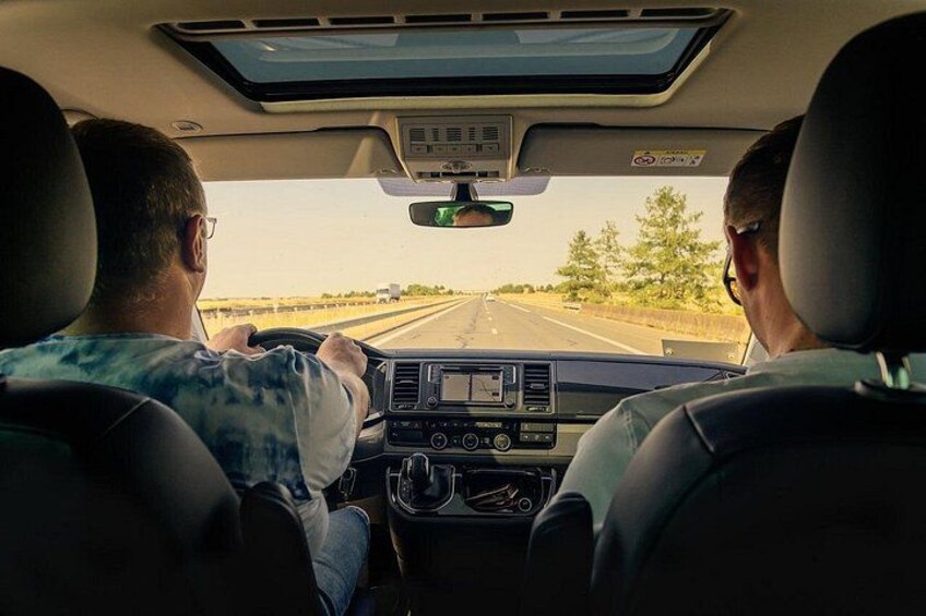 A vehicle interior with a driver and a passenger, a sunroof, a steering wheel, and a dashboard with a GPS screen. 2