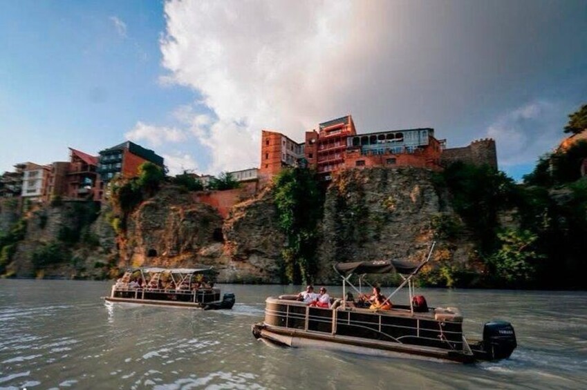 A river with boats, a castle-like building on a cliff, and a clear sky. 5