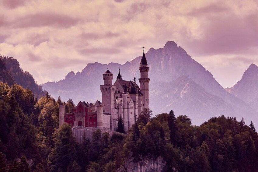 A castle with towers, surrounded by forest and mountains. 4
