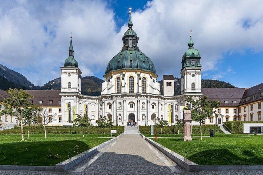 A large church with a green dome and two towers, surrounded by a well-maintained lawn and a cobblestone pathway. 5