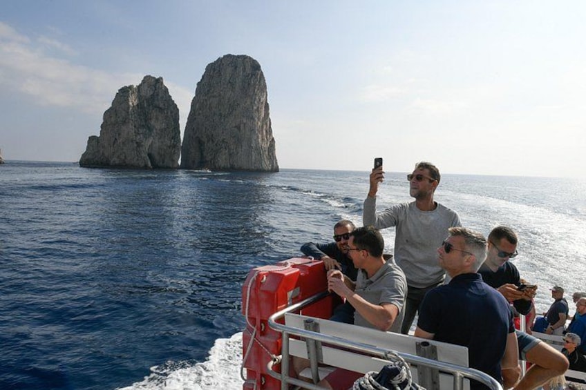 Un grupo de personas en un barco con una formación rocosa al fondo. 1