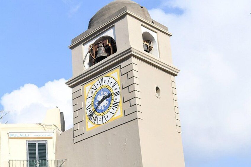 Un campanario con una campana, cielo despejado y un edificio con un cartel. 2