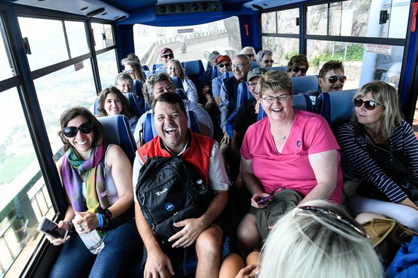 Un grupo de personas sentadas dentro de un autobús con ventanas amplias. 4