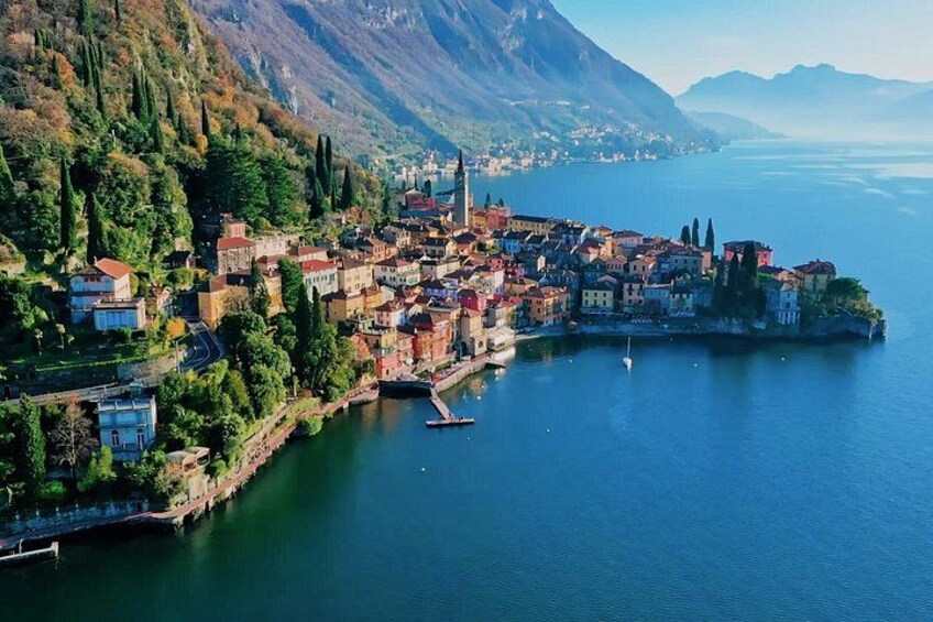 A coastal town with buildings along the water, a mountain in the background, and a clear sky. 3