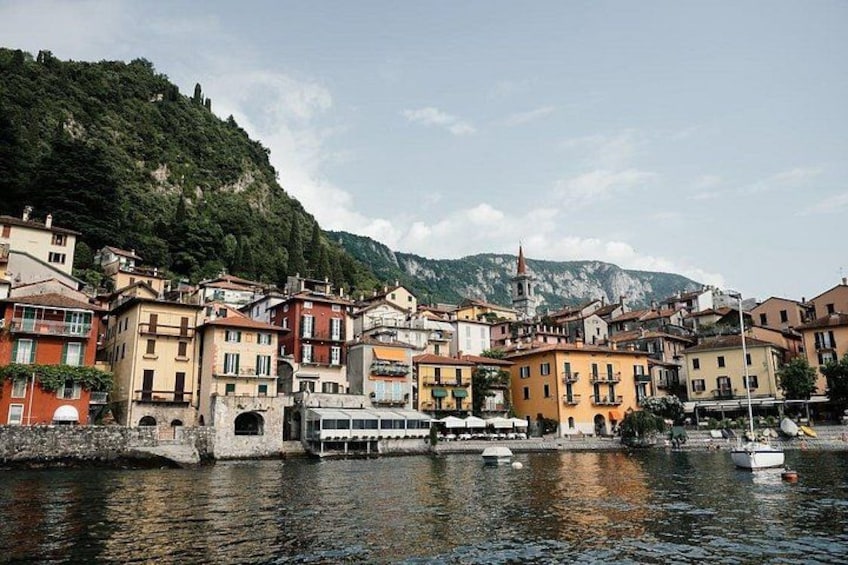 A coastal town with colorful buildings, a church, and a mountain backdrop. 1