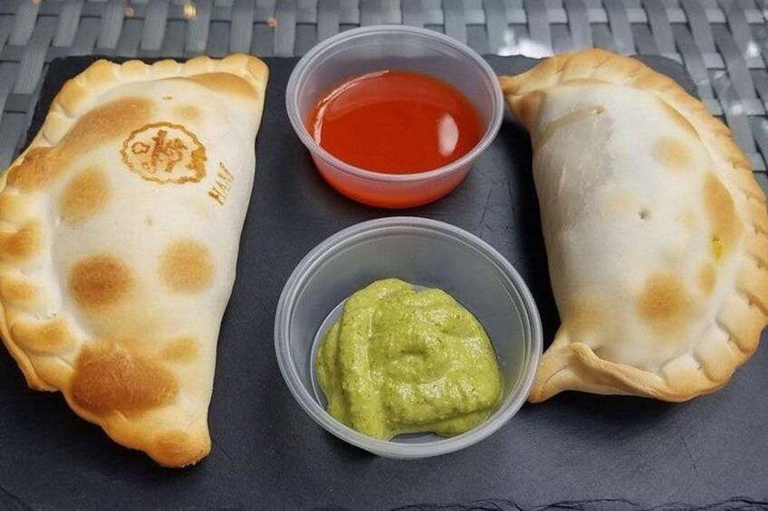 Deux empanadas accompagnés de sauces pour tremper et un récipient de guacamole. 2