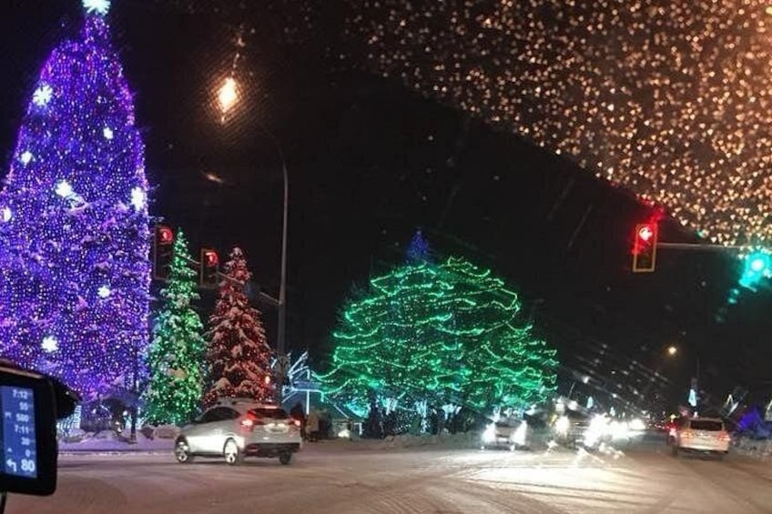 Une rue de nuit, illuminée par des sapins de Noël et des feux de signalisation. 3