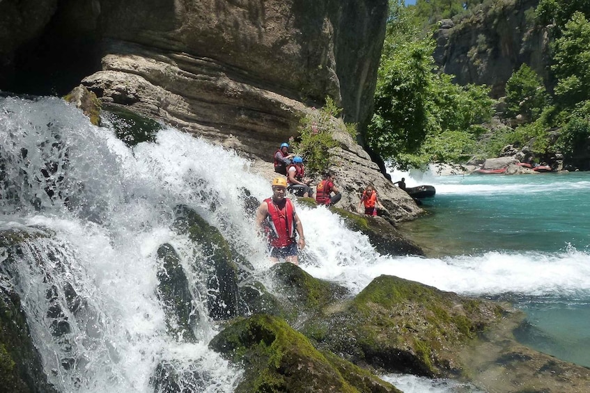 A group of people in red life jackets navigating a rocky waterfall. 3