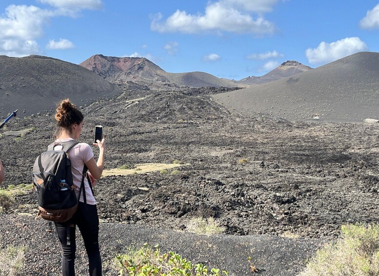 En person fotograferar ett vulkaniskt landskap med berg i bakgrunden. 5