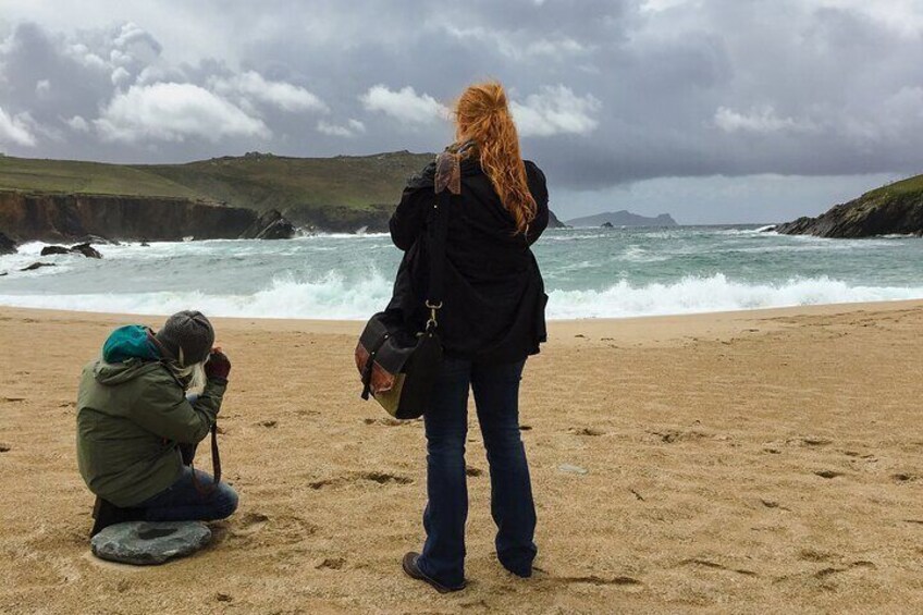 A beach with waves, a photographer, and a person standing. 4