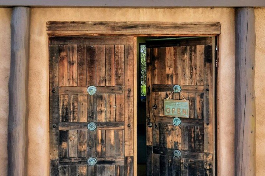 A rustic wooden door with a sign that reads 'OPEN' and a metal latch. 1