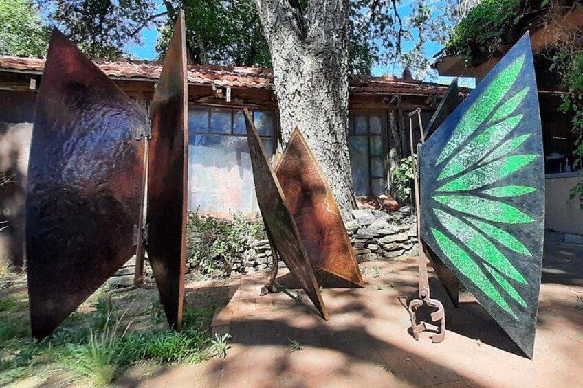 Outdoor sculptures, a tree, and a building with a tiled roof. 2