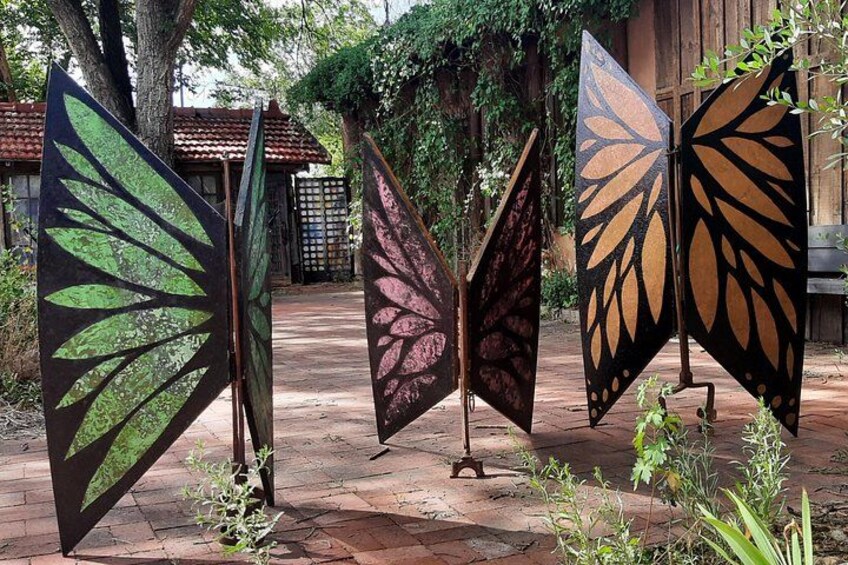 Three large, leaf-shaped metal sculptures in a garden. 3